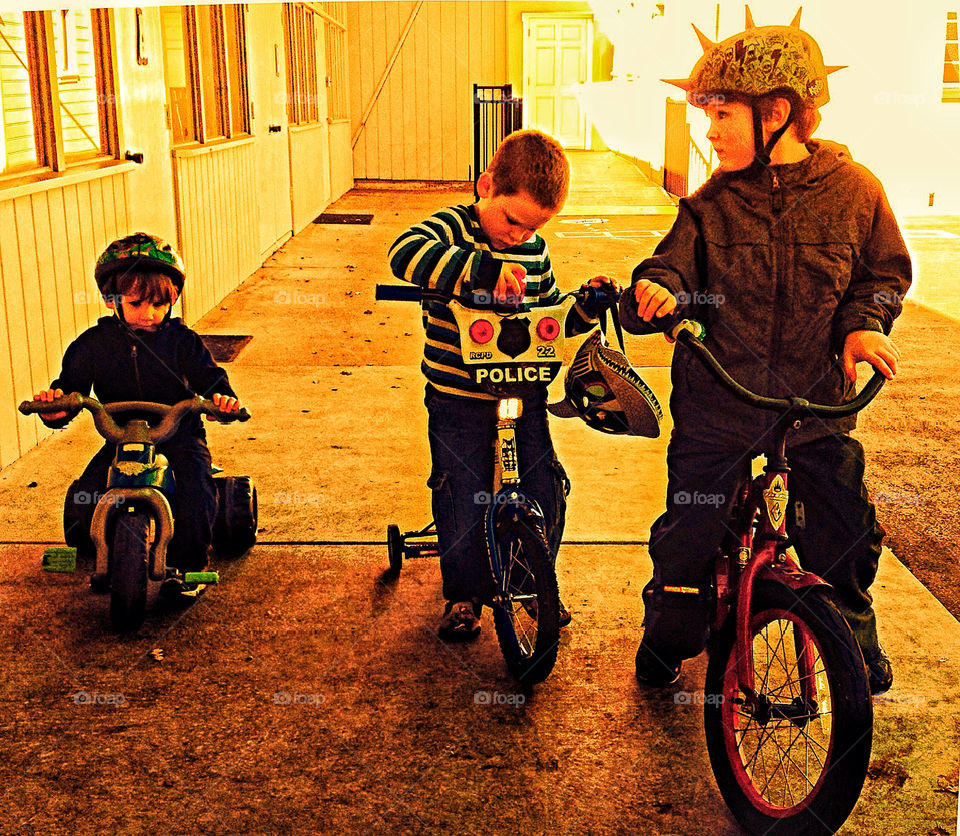 Three young brothers get ready to ride bikes in a heavenly ray of