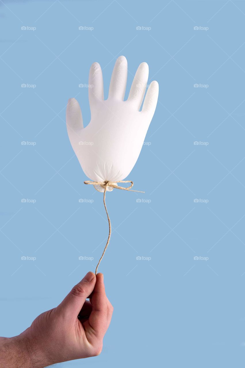 Hand holding medical glove as balloon
