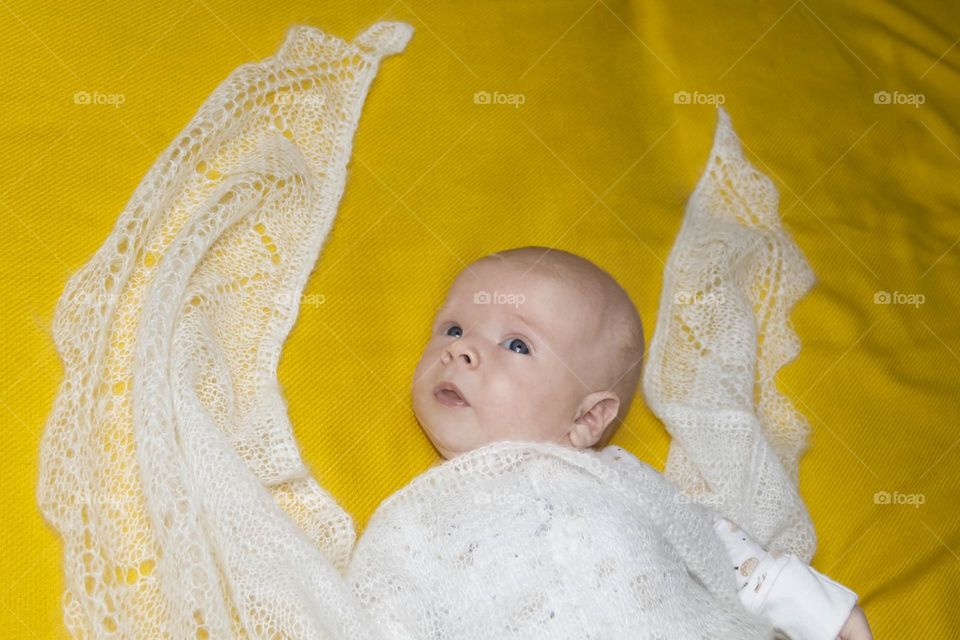 A newborn baby on a yellow and gray background. A photo shoot in the style of Newborn and lifestyle.