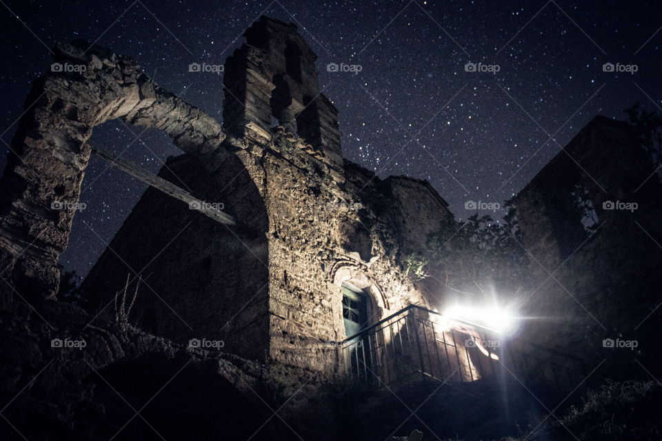 darkness and light on the ruins of an old temple and monastery with the stars background