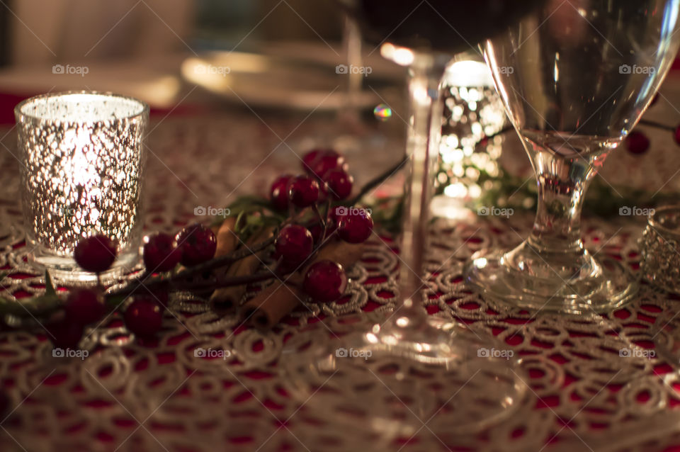 Festive holiday Christmas table with cranberry and cinnamon decoration and silver candlelight with wine glasses 