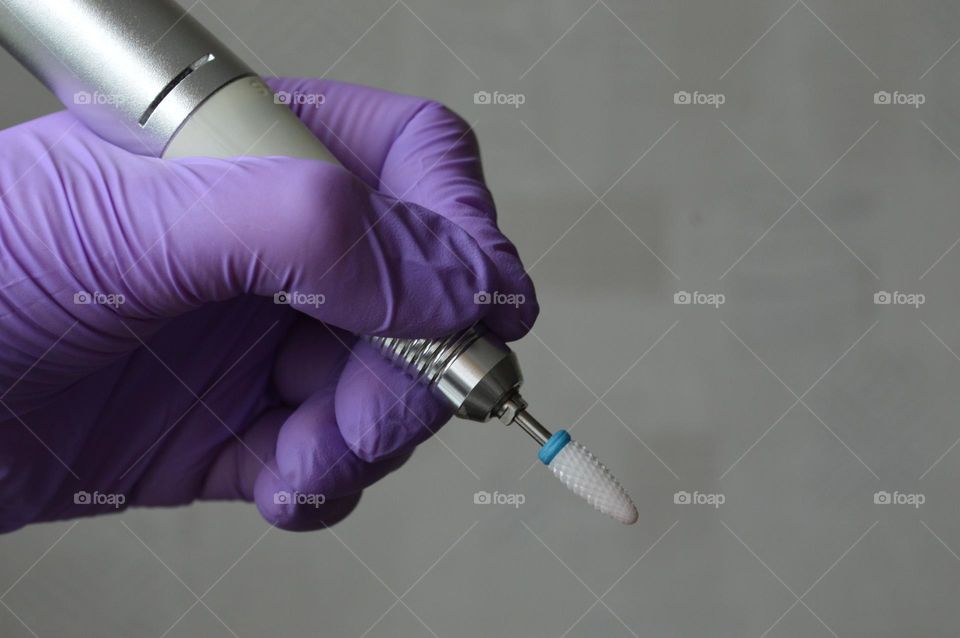 Manicure tools are held by a manicurist in rubber gloves