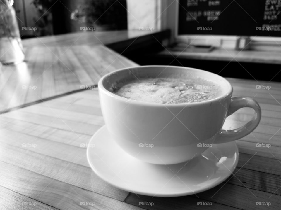 black and white cup of coffee on wood counter top.