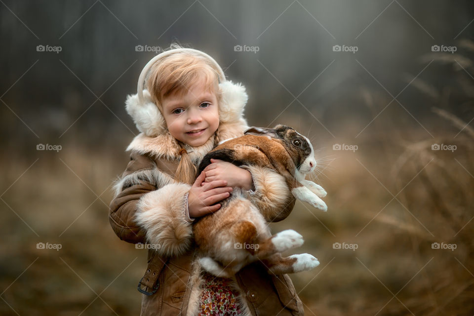 Cute Little girl with bunny in a forest at misty autumn evening 