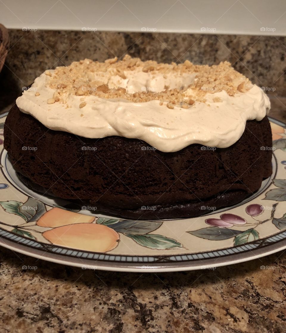 Chocolate bundt cake with peanut butter whip cream & sprinkled with nuts 