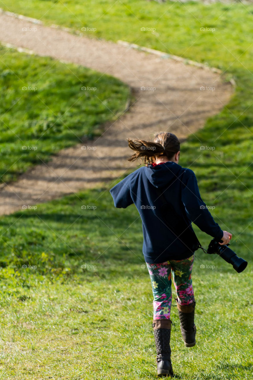 Photographer child happy skipping down a hill in the sun
