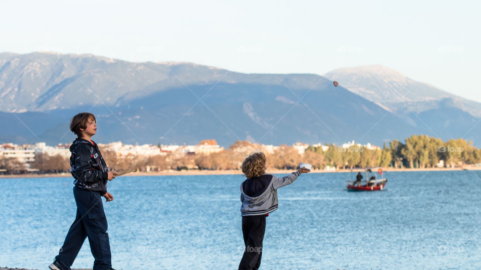 two boys throwing and catching stones at the beach