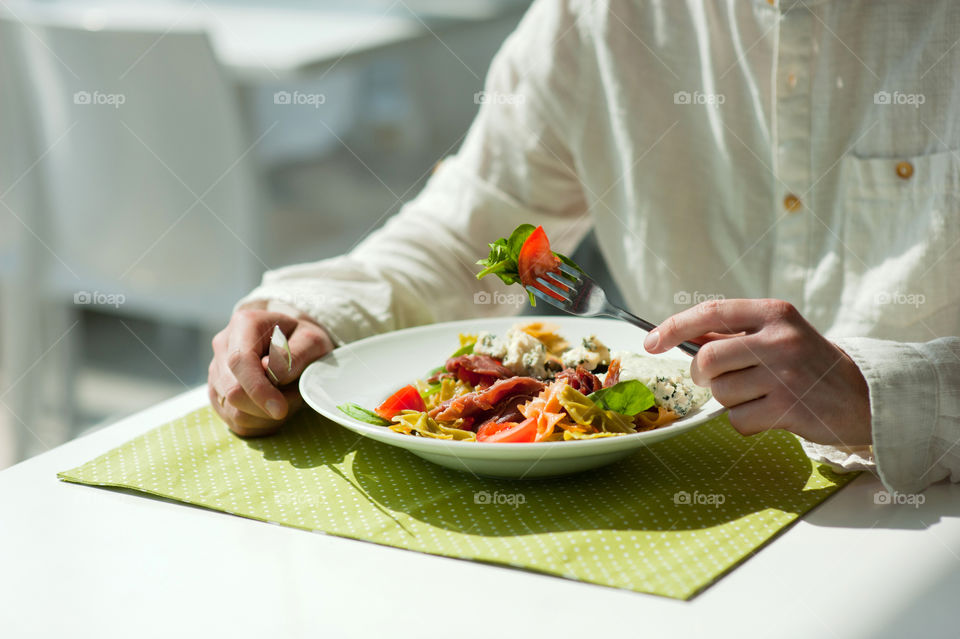 close-up of a young man eating a salad in a light kitchen