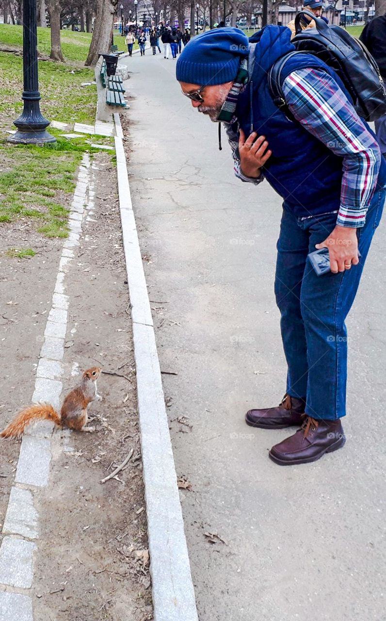 Man talks to squirrel calmly, expressing his love for animals.