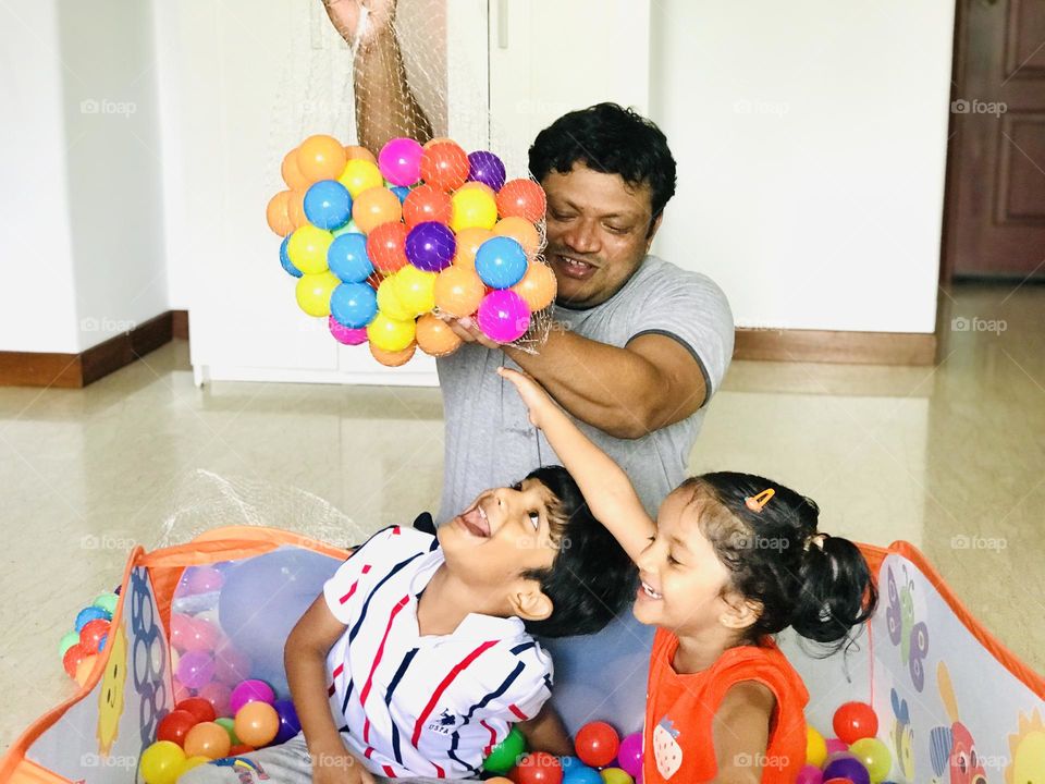 Father has a great fun with kids in house by playing in ball pit😃