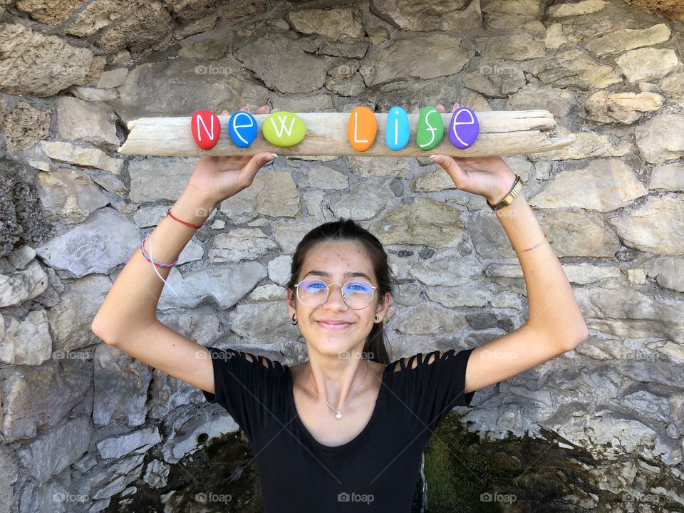 New life message with colored stones held by a young girl with glasses
