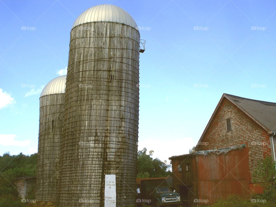 Two silos, tall& shorter, near barn.