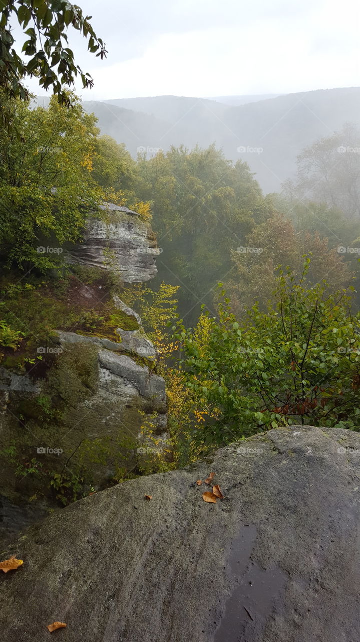 Misty mountain overlook in early autumn from rock ledge during a hike in the forest.