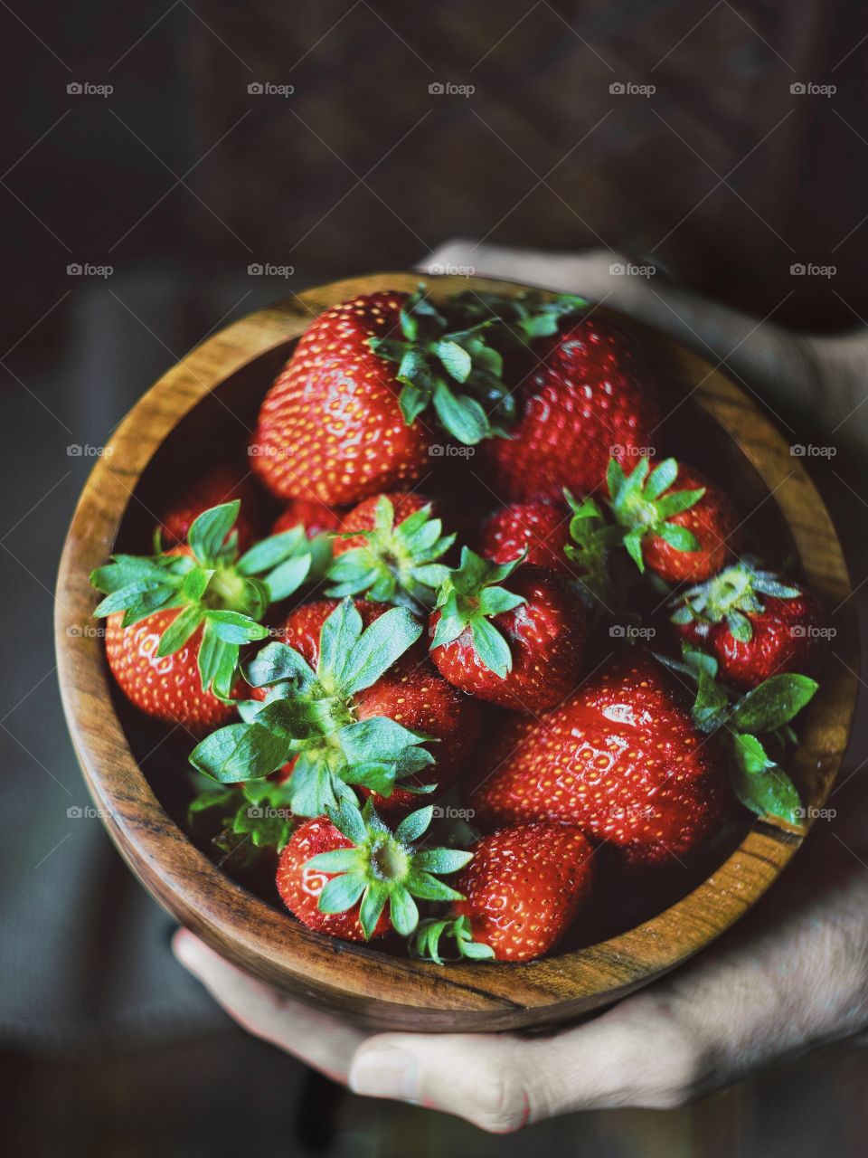 Hands holding bowl with strawberries