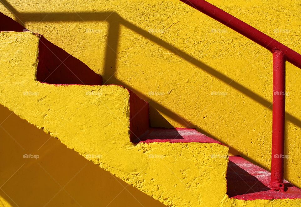 Close up shot of a yellow life guard tower with stairs outdoors in sunlight during summer