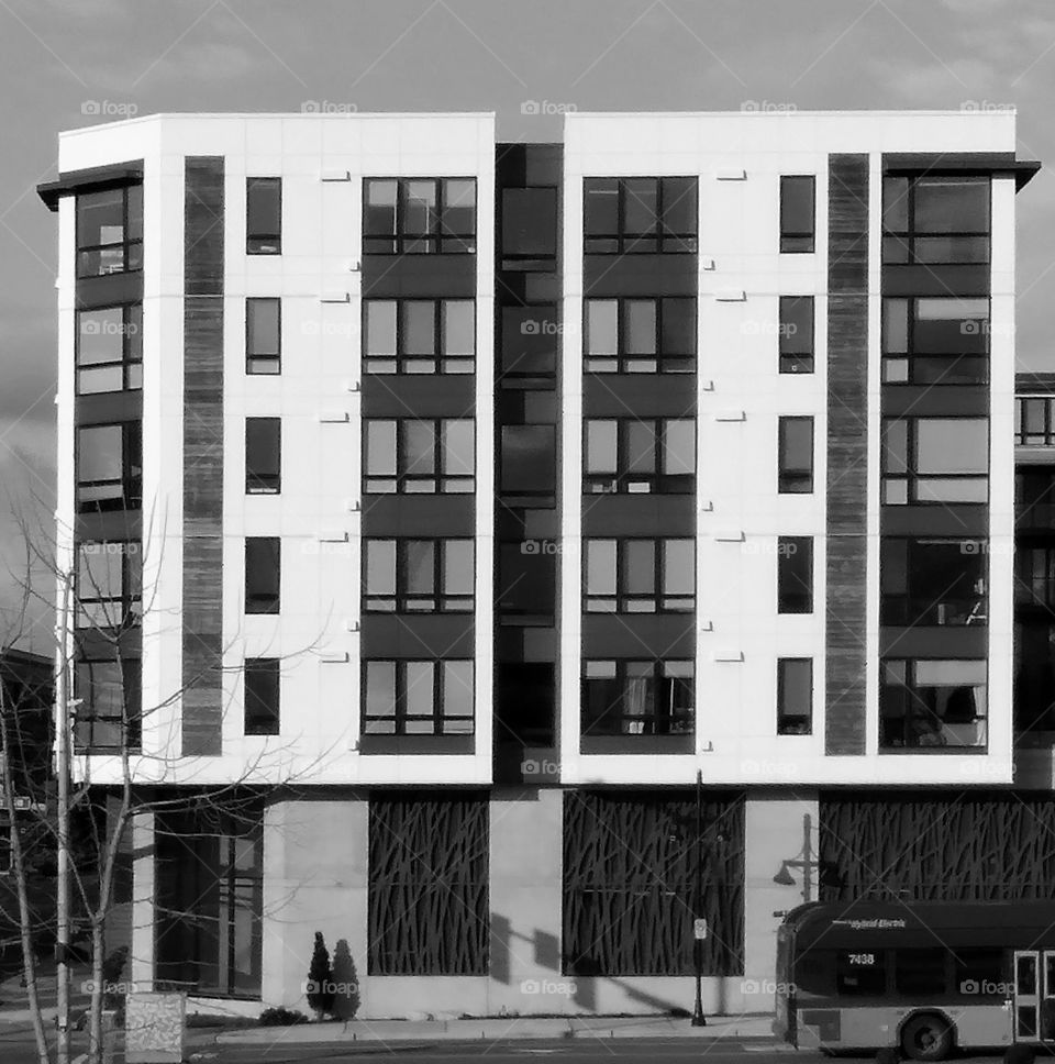 An building with a base smaller than the apartments above with shops on the floor level.