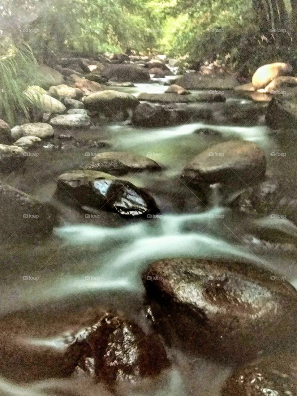 Mountain stream in winter. Large boulders are littered with  snowy patches