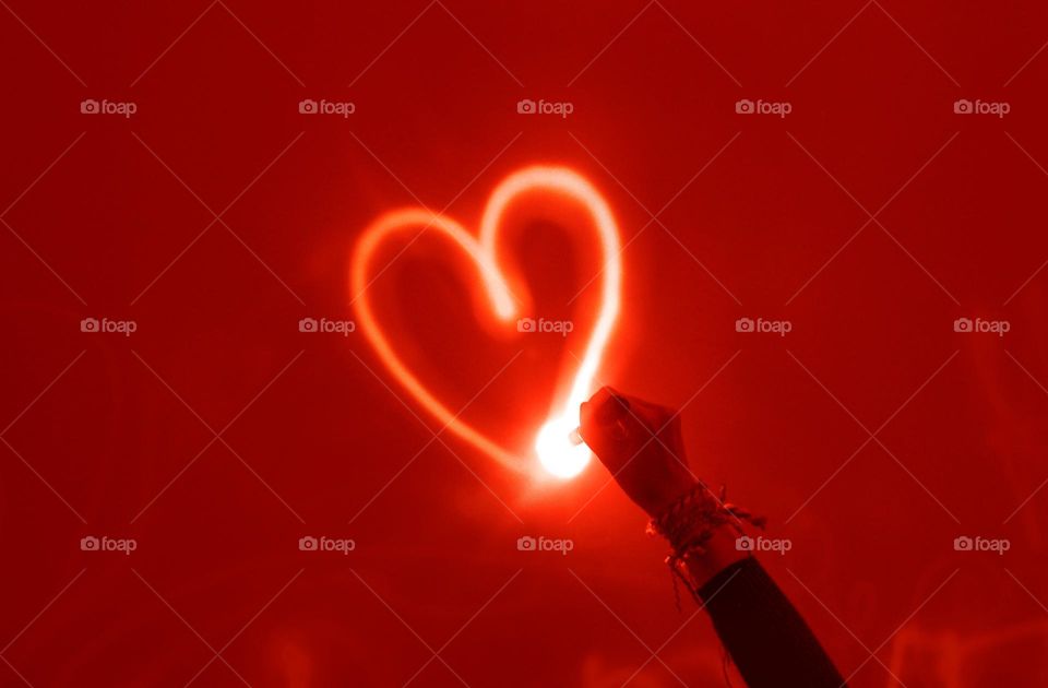 Drawing love heart with light in the red dark background