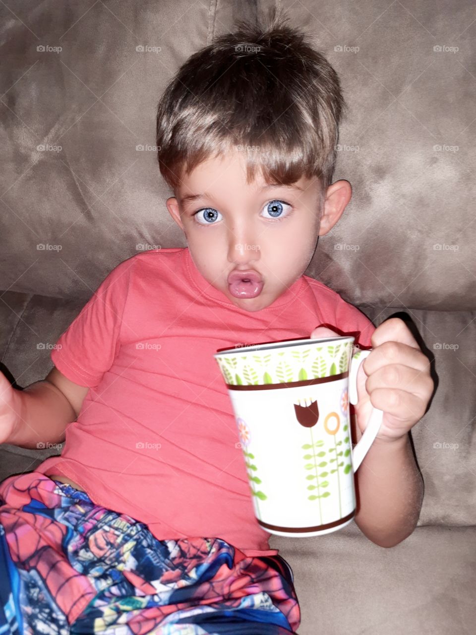 blue-eyed child drinking coffee and pouting
