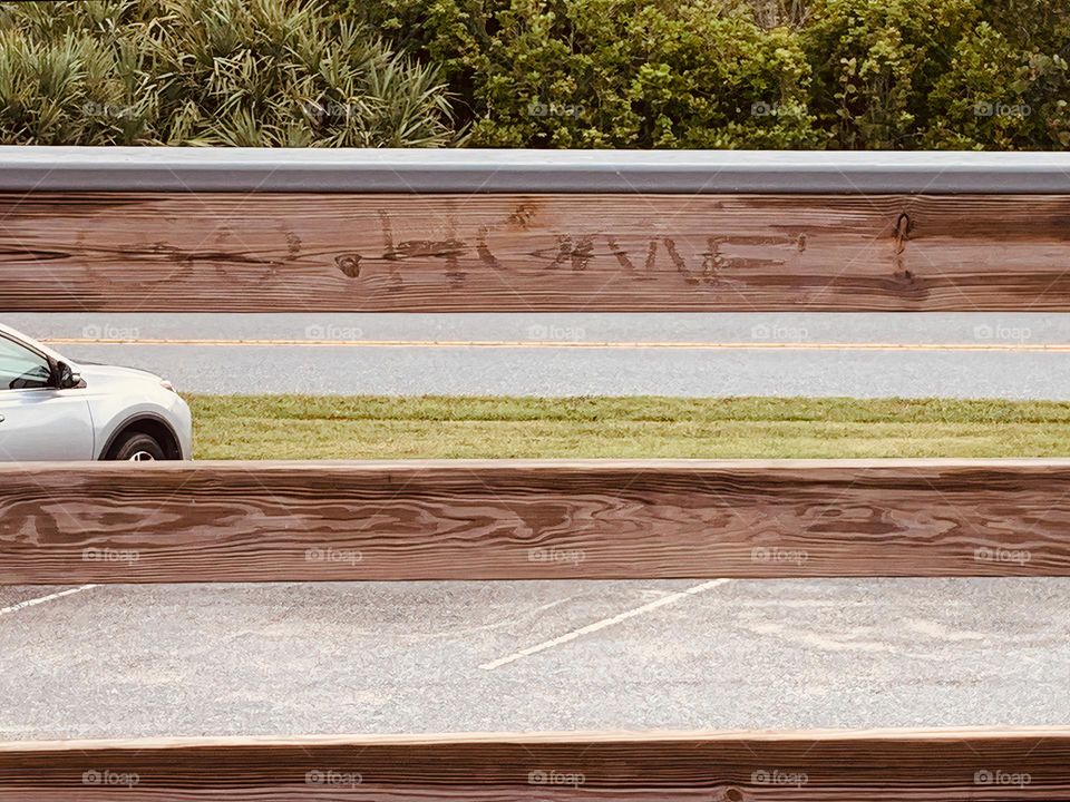 GO HOME Inscription on wooden railings in front of a parking lot in a tropical environment with a vehicle.