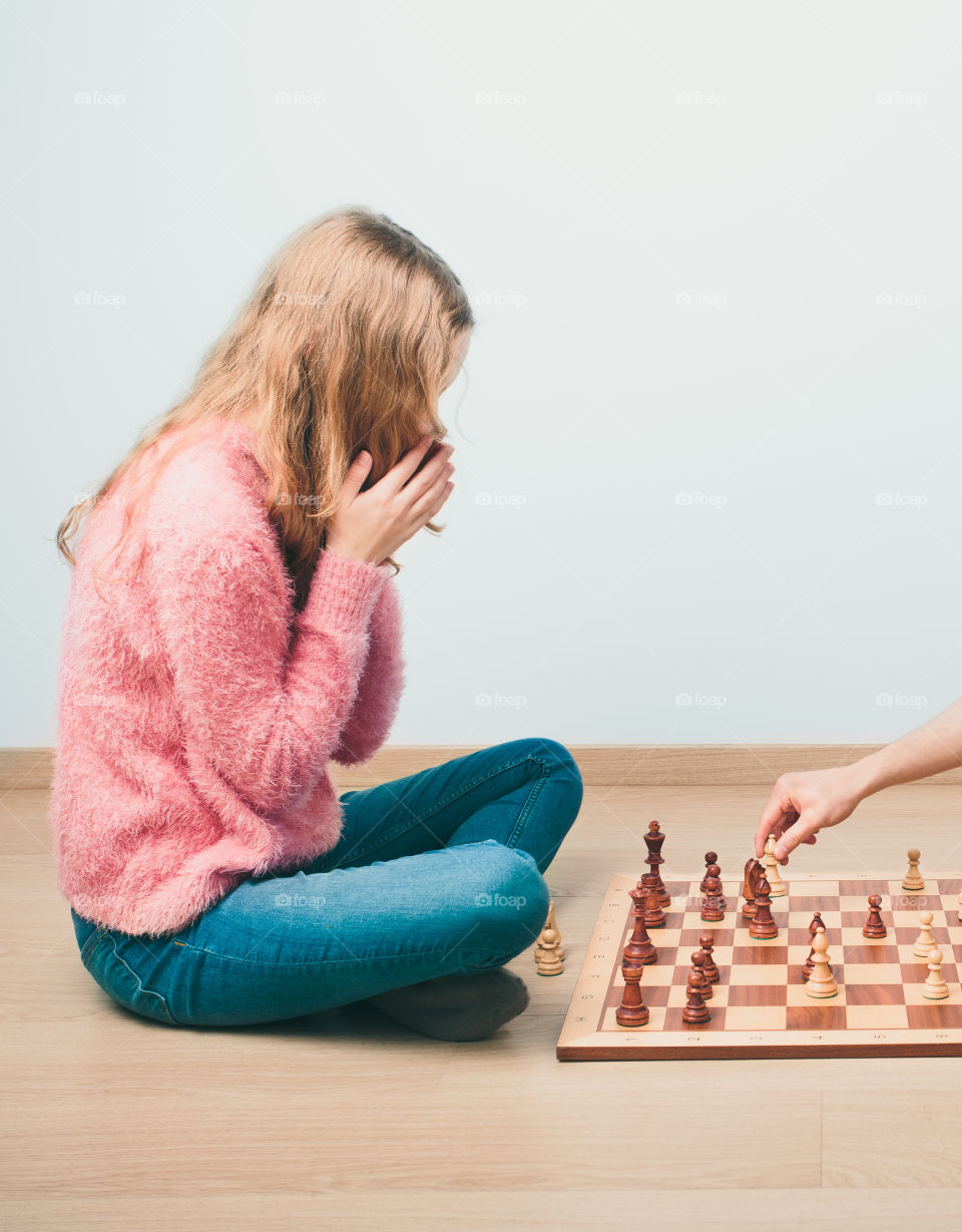 Checkmate. Girl is surprised by last move her opponent in chess game. Copy space for text at the top and bottom of image