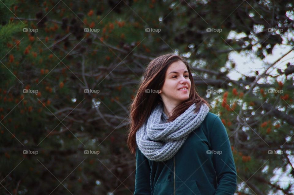 Portrait of a girl dressed in green with scarf smiling, trees, nature, proud.