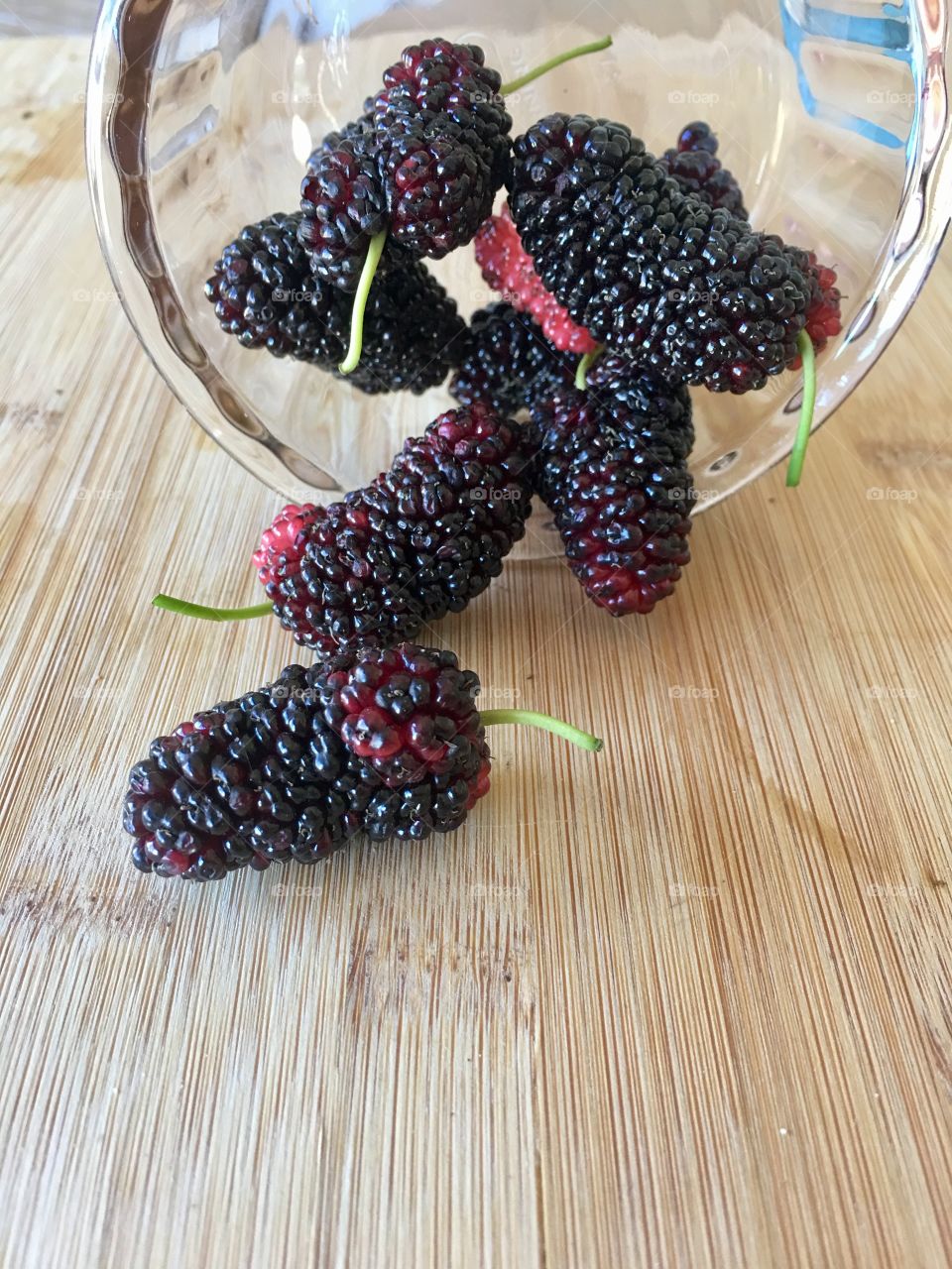 Freshly picked organic juicy ripe mulberries spilling out of glass preserve canning jar onto bamboo wood surface, in preparation for canning, copy and text space, food dessert jam ingredient, power food nutritious