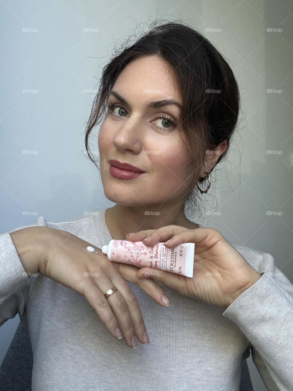 Woman portrait with the product, she holding the hand cream in her hands