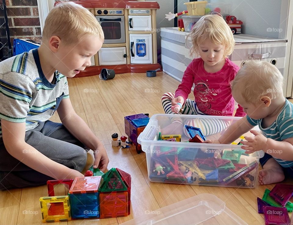 Three young children play with educational magnetic toys on an indoor activity day 