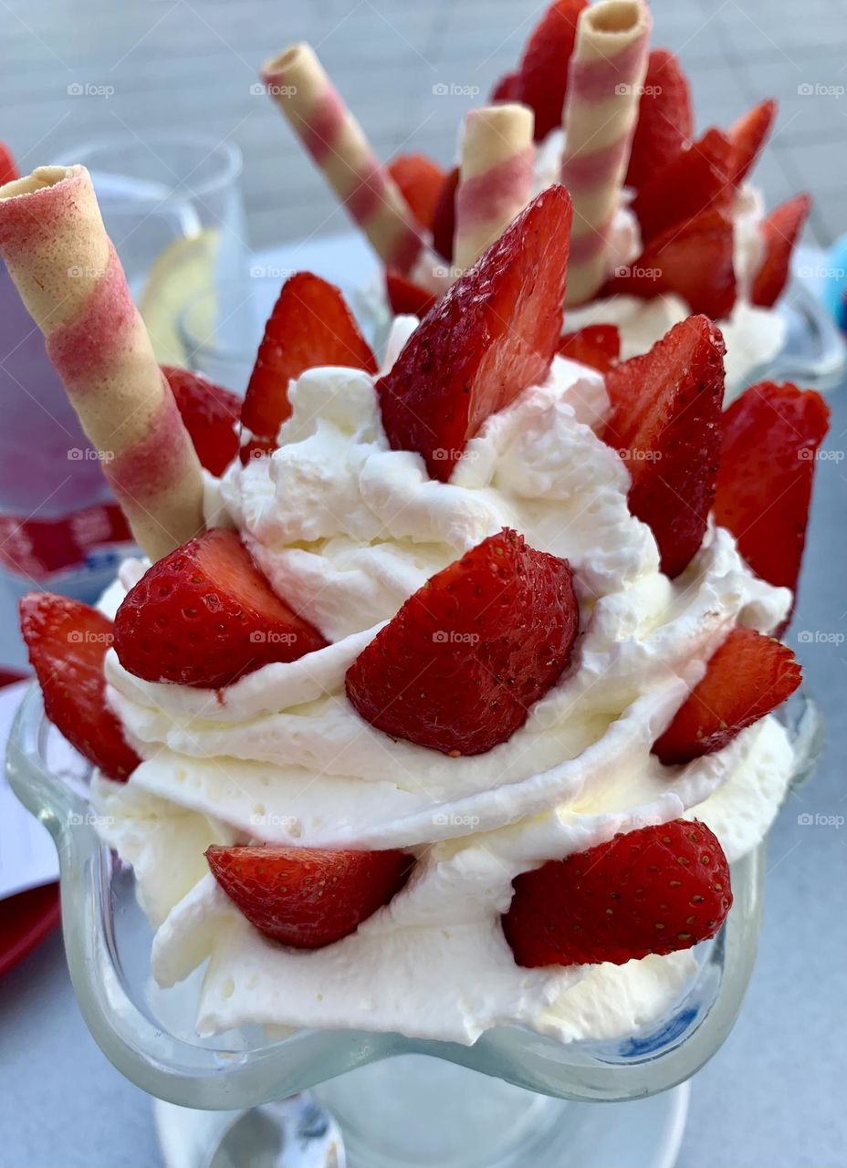 Yummy strawberries with whipped cream on crystal bowl decorated with biscuits 