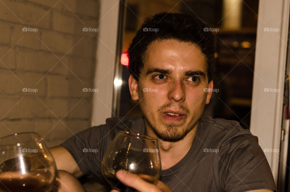 Man looking suspicious and disgust while drinking beer from a glass in bar at night 