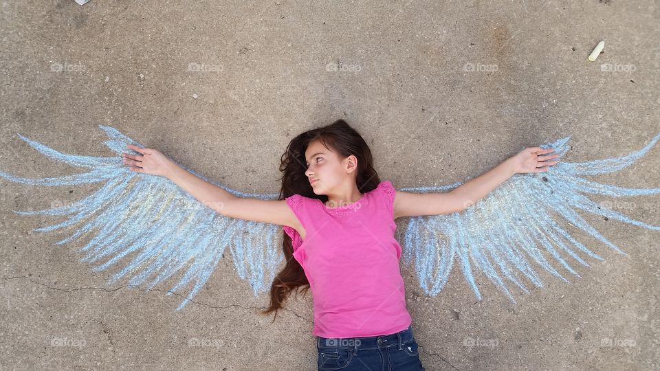 Girl lying on street over the drawn wings