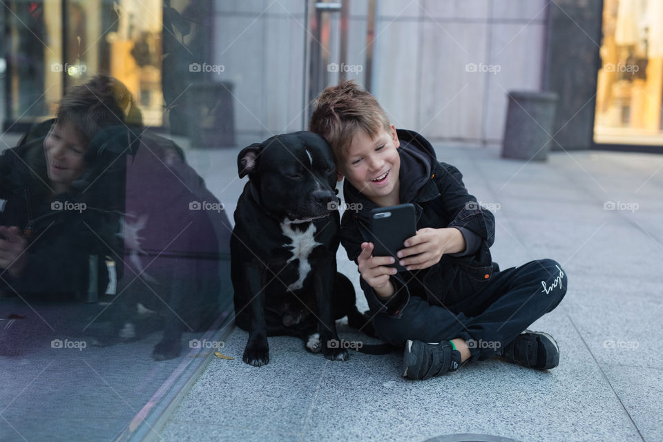 cute baby and his friend dog, sitting together on the street, and taking a selfie. quarantine distance, empty city. child and dog. friends. no one around