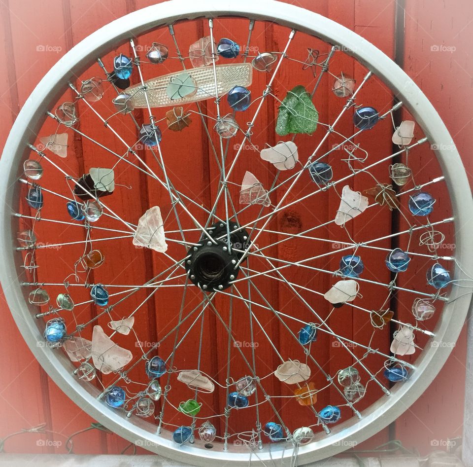 Random piece of art with various gems sitting on a fence.