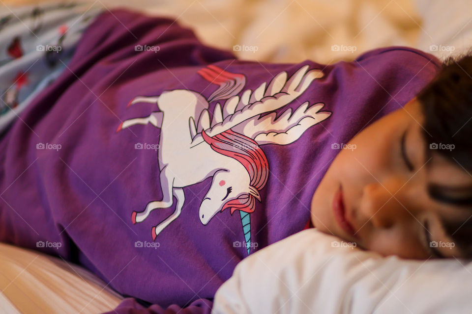 Sleeping little girl in pajamas with unicorn