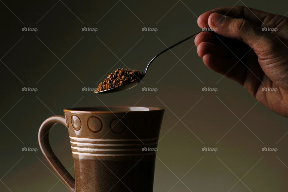 hand pouring coffee on mug with a spoon