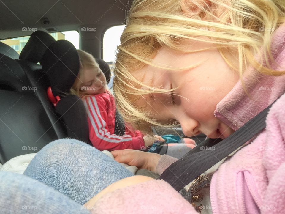 Young girls sleeping in a car. Three years old and five years old from Sweden, the car is a Volvo V70.