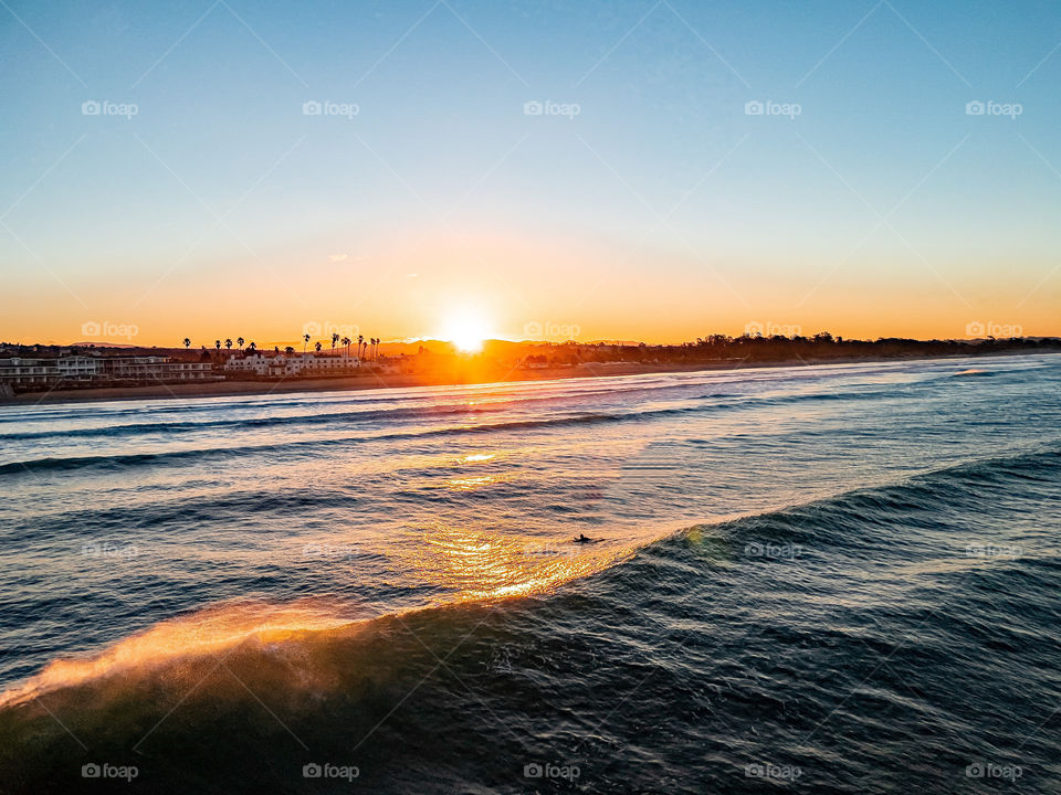 Sunrise light shines on the waves and surfers at Pismo beach in California. 