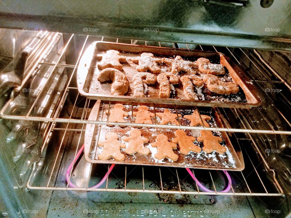 Two trays holiday gingerbread cookies baking in the oven