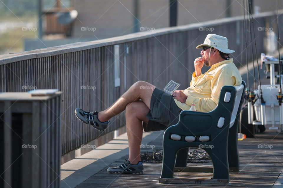 Man chilling and eating snack in the port of the sea for fishing 