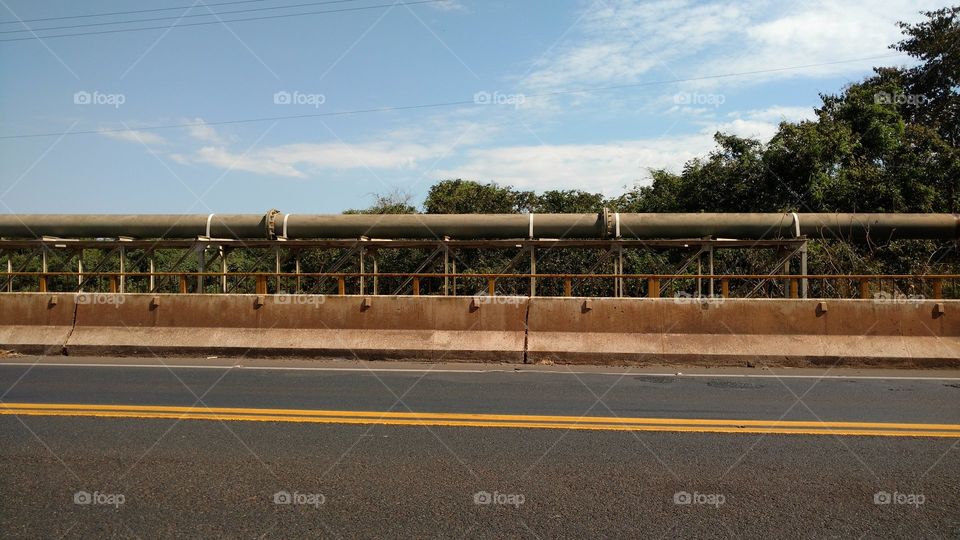 Olha que imagem top! Asfalto sobre a ponte do rio e tubulação de água.
