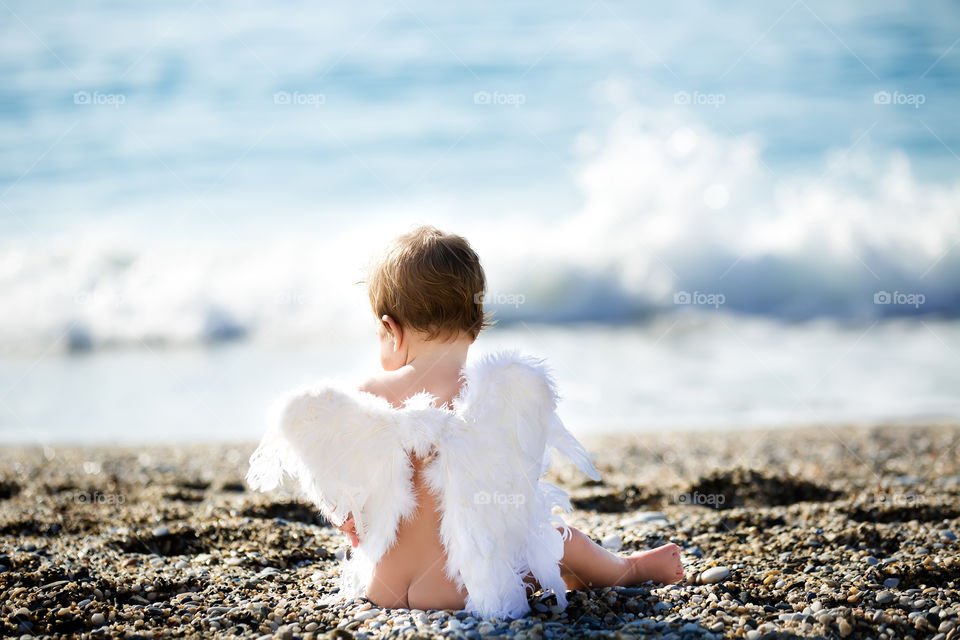 Girl sitting near beach with angel's wings