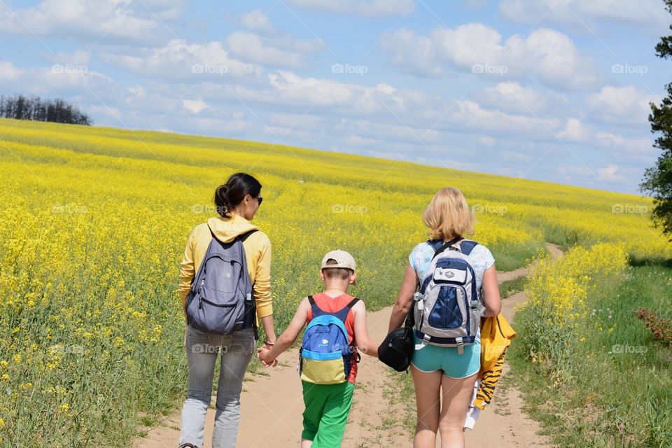 family walking on a road rapeseed field summer time