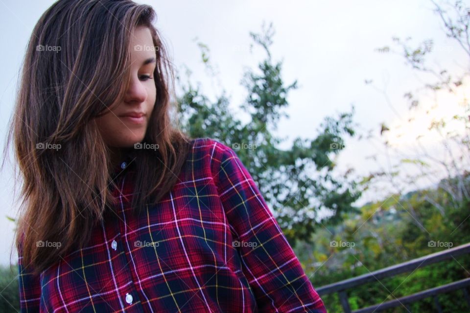 Girl wearing flannel, nature in the background, eyes closed, thinking, lightly smiling