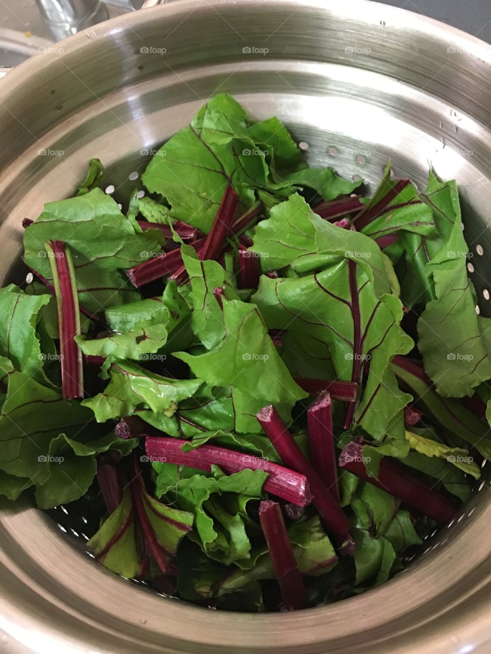 Beet greens in a stainless steel colander