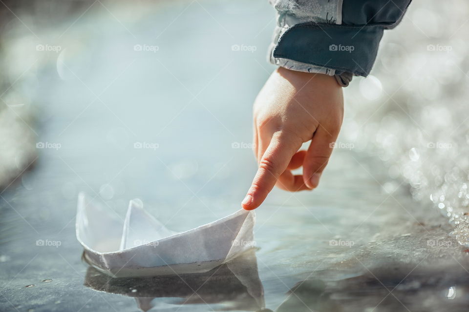 Little girl with paper boat on creek 