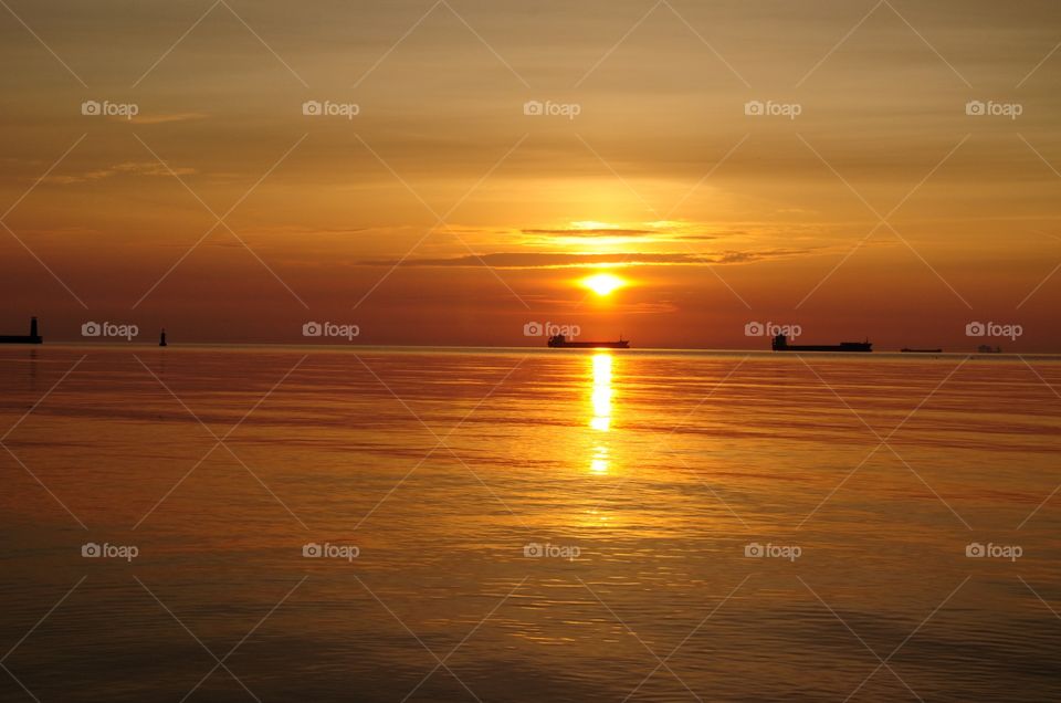 Beautiful bright sunrise over the Baltic in Gdynia, Poland - shops on horizon, silhouettes and calmness 