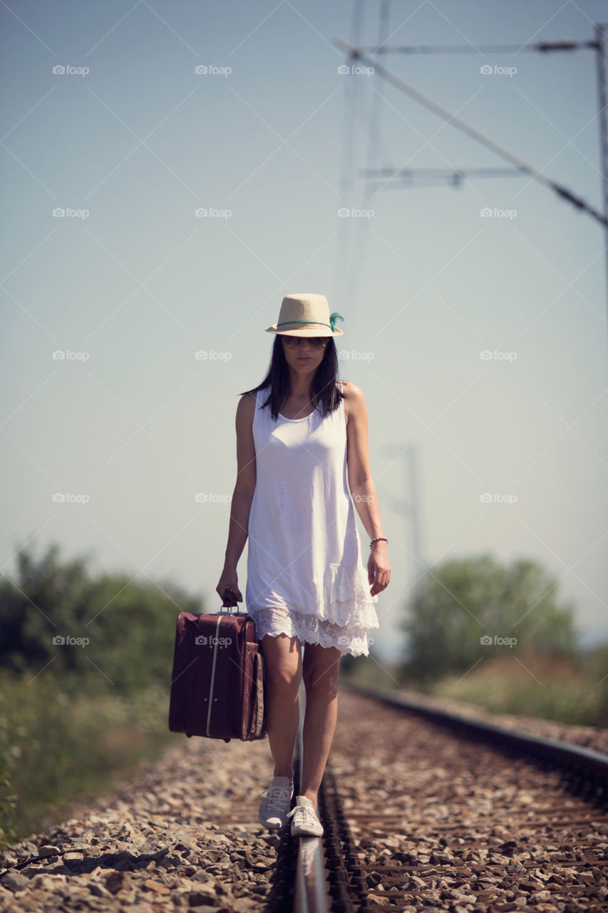 Woman wearing hat walking on train track