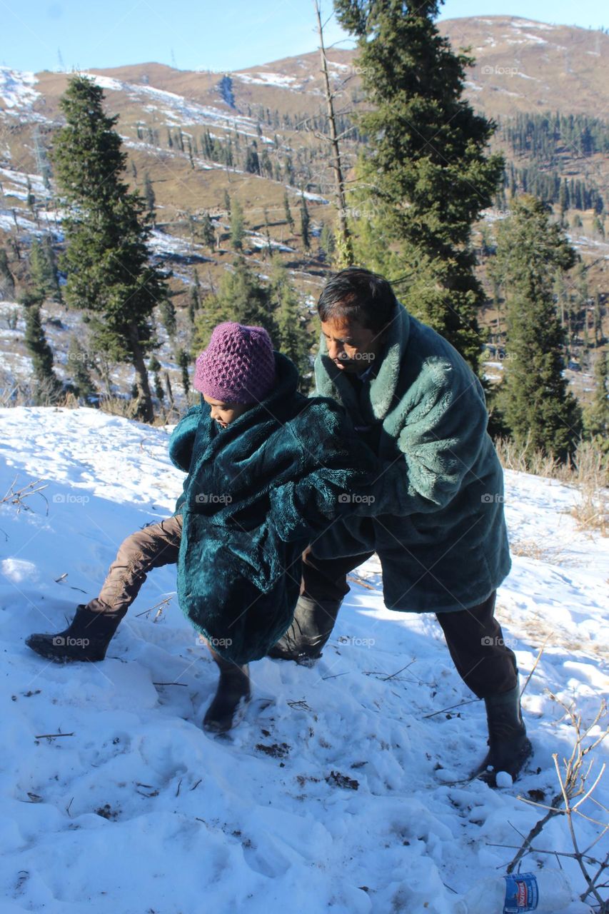 Kid with his grandpa enjoying in the nature covered with snow in the winter