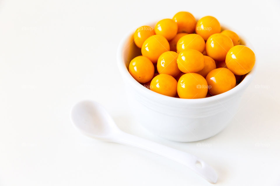 product fresh gooseberries in s white bowl with white spoon on pure white background